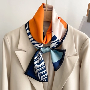 Detail of multi-color paisley silk scarf styled on a beige blazer and wooden hanger