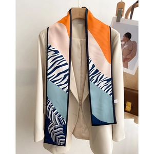 Detail of multi-color geometric print twilly scarf draped over a beige blazer