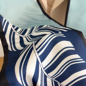 Macro shot of silk scarf showing navy paisley patterns and premium smooth texture