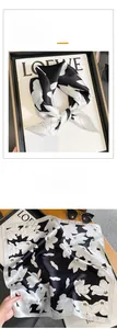 Detail of silk square scarf featuring monochrome magnolia print and premium satin texture