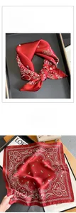 Detailed view of red silk square scarf with white paisley pattern and soft silk texture