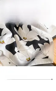 Close-up of silk square scarf featuring white magnolia pattern and fine stitched edges