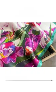 Detail view of purple floral silk scarf showing fine green edge stitching and fabric texture