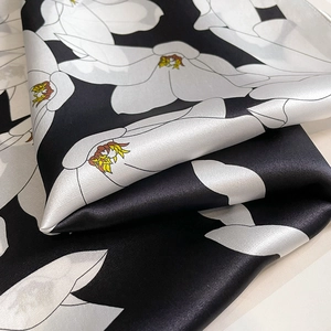 Elegant silk scarf with white floral pattern on black background and fine rolled edges