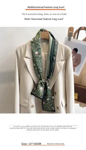 Détail d'un foulard étroit en soie vert vintage avec fleurs et rayures sur un blazer