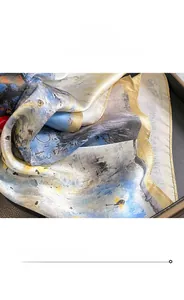 Détail des bords roulés dorés et du motif de peinture abstraite sur une écharpe en soie