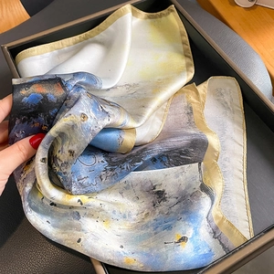 Carré en soie imprimé artistique avec motifs bleus et dorés présenté dans son coffret