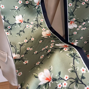 Gros plan d'un foulard étroit en satin fleuri noué sur le col d'un blazer blanc chic