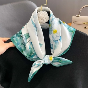 Elegant white silk square scarf with blue camellia floral print on a black sweater
