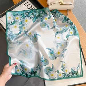 Silk square scarf with camellia floral print and green border on wooden background