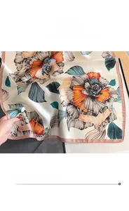 Close-up of pink fine stitched edges and colorful floral print on silk scarf material