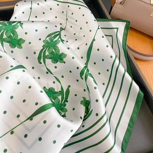 Carré en soie blanche élégant avec motifs floraux verts et pois sur un présentoir