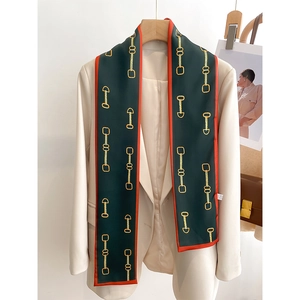 Détail d'un foulard en soie à imprimé chaîne dorée sur un blazer crème chic