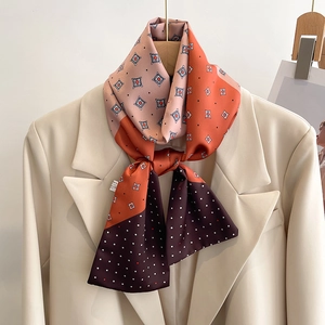 Détail d'un foulard en soie à motif géométrique stylisé sur un blazer de couleur ivoire
