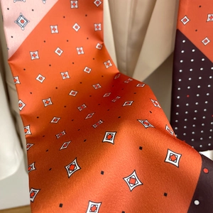 Détail d'un foulard en soie orange avec motifs géométriques et texture soyeuse