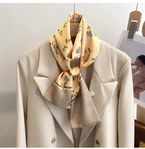 Détail d'un foulard en soie à fleurs jaunes noué sur un col de blazer crème