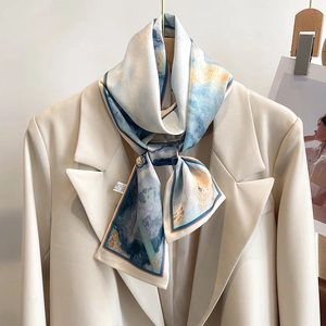 Detail of artistic oil painting silk scarf styled with a beige blazer on a wooden hanger