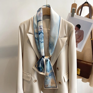 Elegant blue marble silk skinny scarf tied on a beige blazer as a stylish necktie