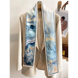 Detail of silk-like neckerchief with blue marble pattern draped on a beige blazer