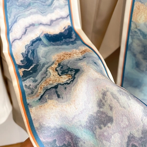 Detailed macro shot of silky abstract marble print scarf with contrast blue and orange edges