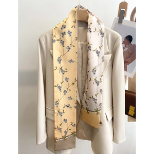 Détail d'un foulard en soie beige à fleurs drapé sur une veste de costume blanche