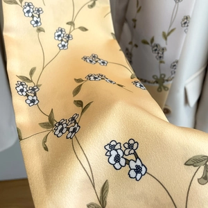 Vue détaillée d'un foulard en satin jaune gingembre avec imprimés floraux et texture soyeuse