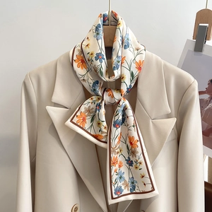 Gros plan d'un foulard étroit en soie à fleurs sur le revers d'un blazer blanc élégant