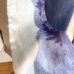 Macro shot of silk-like neck scarf showing blue oil painting landscape pattern details