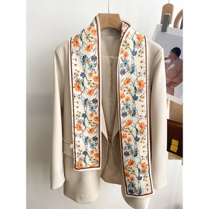 Détail d'un foulard étroit en soie à fleurs sur le col d'un blazer blanc