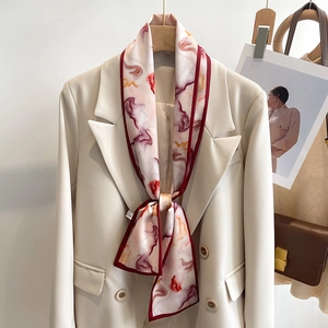 Abstract print silk-like skinny scarf with red borders styled on a beige blazer