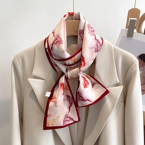 Detail of pink marble print skinny scarf styled on a beige blazer lapel