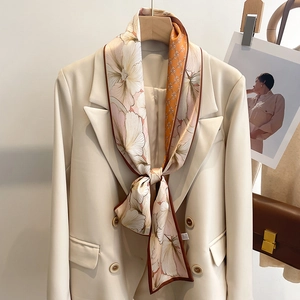 Élégant foulard en soie à imprimé floral rose et orange porté sur un blazer beige
