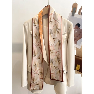 Détail de l'écharpe étroite sur blazer beige montrant les motifs floraux réversibles