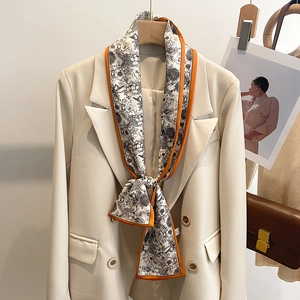 Foulard étroit à fleurs avec bords orange porté sur un blazer beige élégant