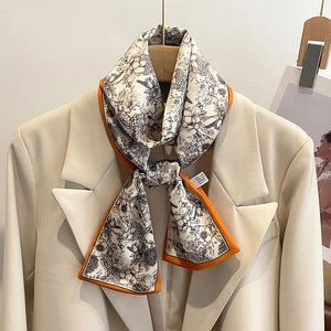 Détail d'un foulard en soie à fleurs avec bords orange contrastés sur un blazer