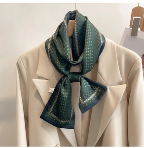 Détail d'un foulard en soie vert foncé à motif géométrique porté avec un blazer beige