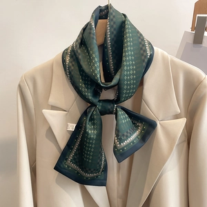 Détail de la texture d'un foulard en soie vert avec imprimés géométriques sur blazer