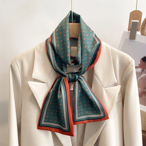 Détail macro du foulard étroit vert foncé fleuri sur un blazer blanc chic