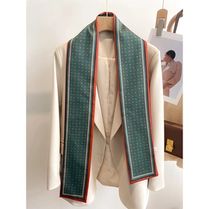 Détail d'un foulard étroit vert foncé à fleurs orange sur une veste de blazer