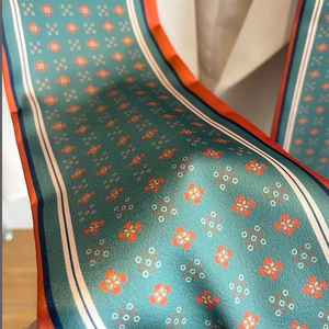 Vue macro d'un foulard en soie vert avec motifs floraux et bords rayés colorés