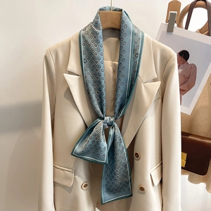 Élégant foulard étroit en soie sarcelle à motifs géométriques sur un costume beige