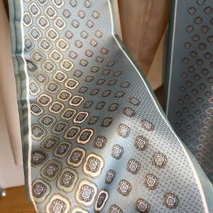 Détail d'un foulard en soie bleu gris avec des motifs floraux géométriques élégants