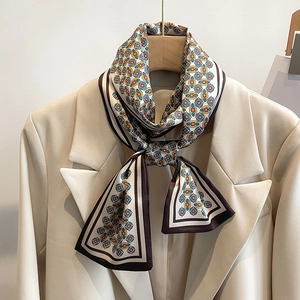 Détail d'un foulard en soie à motif géométrique noué sur un tailleur beige chic