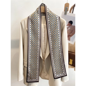 Détail d'une écharpe longue et étroite en soie à pois géométriques sur un blazer