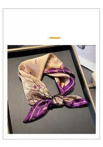Detailed close-up of folded silk square scarf featuring elegant purple and gold wood patterns