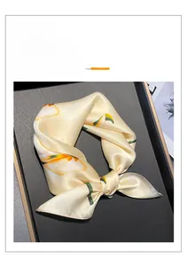 Detail of silk square scarf featuring orange calla lily patterns and satin texture
