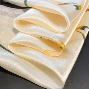 Elegant silk square scarf with yellow and green floral patterns on creamy satin fabric