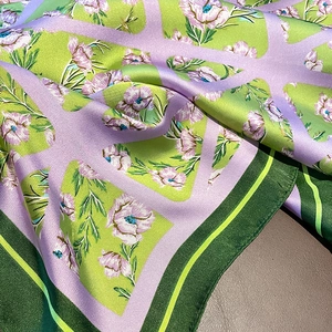 Vista dettagliata di un foulard in raso con motivo floreale verde e viola e trama geometrica