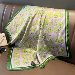 Foulard quadrato in seta con motivi floreali e geometrici su un divano in pelle