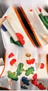 Detailed view of silk scarf with colorful ginkgo leaves and orange rolled edges